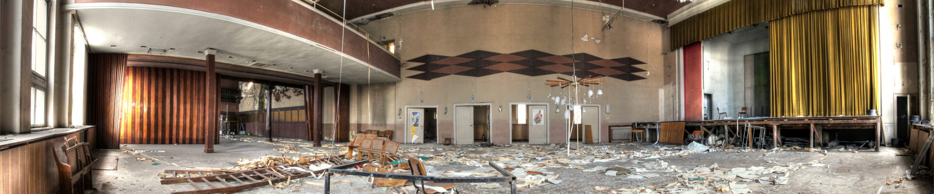 Verlassener Saal mit Bühne und Balkon.
