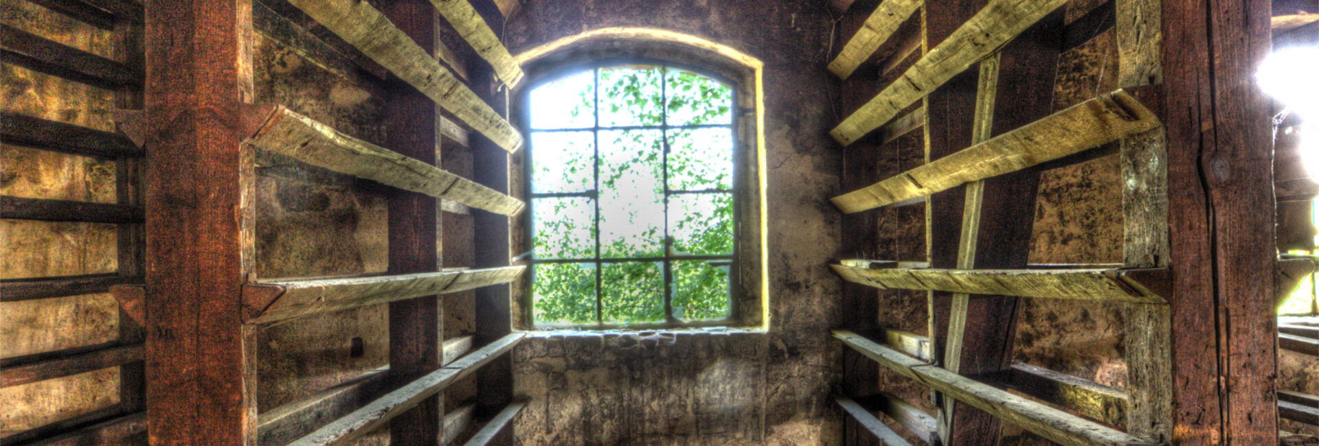 Verfallene Holzhalle mit Fenster und Regalen.